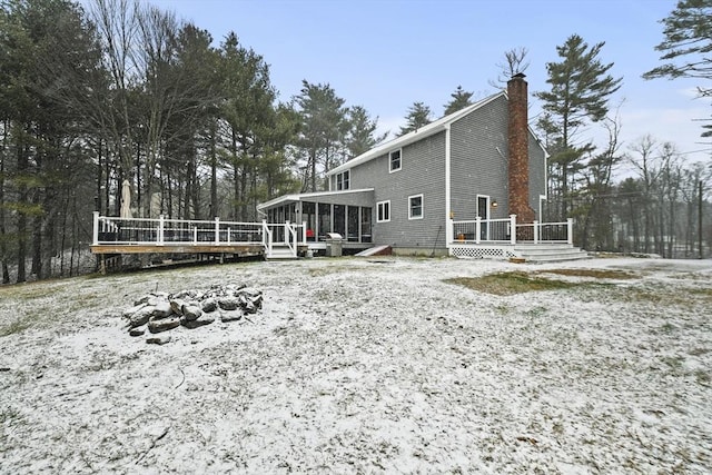 snow covered house featuring a deck and a sunroom