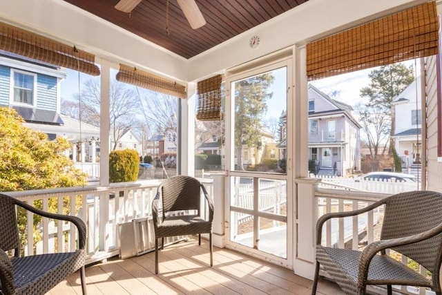 sunroom / solarium featuring a residential view, wooden ceiling, and ceiling fan