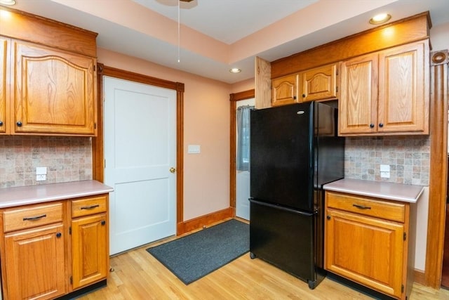 kitchen with tasteful backsplash, light wood-style flooring, light countertops, and freestanding refrigerator