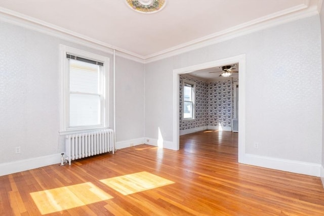 spare room with radiator, baseboards, light wood-style floors, and ornamental molding