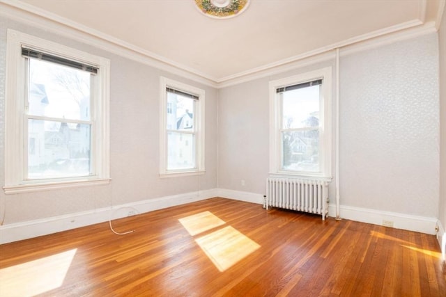 unfurnished room with radiator, a healthy amount of sunlight, and wood finished floors