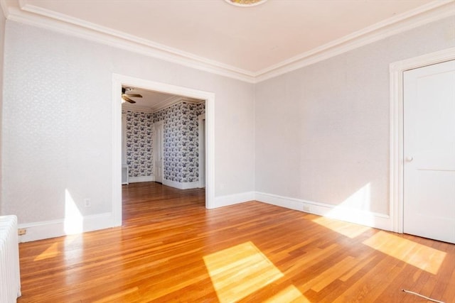 spare room with baseboards, wallpapered walls, radiator heating unit, ornamental molding, and light wood-type flooring