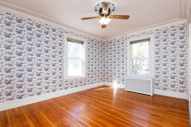 spare room with plenty of natural light, wallpapered walls, and radiator heating unit