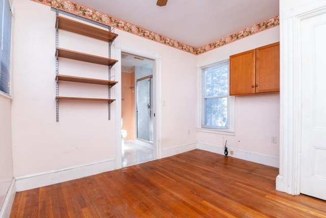 empty room featuring baseboards, wood finished floors, and a ceiling fan