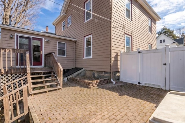 rear view of property with a patio area, fence, a deck, and a gate