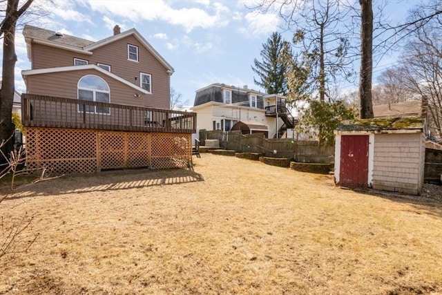 back of house with a deck, an outdoor structure, fence, and a shed