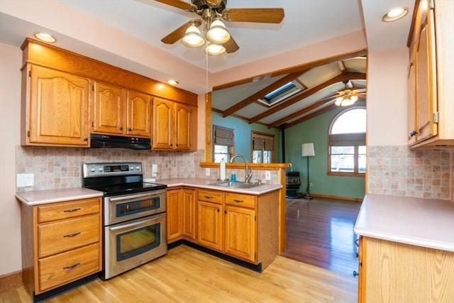 kitchen with under cabinet range hood, double oven range, lofted ceiling with beams, a sink, and a peninsula