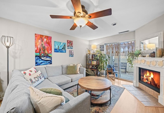 living room with visible vents, a ceiling fan, wood finished floors, and a fireplace