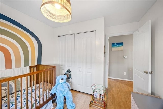 bedroom with light wood finished floors, baseboards, and a closet