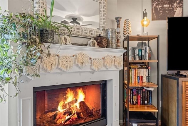 interior details with a lit fireplace and ceiling fan