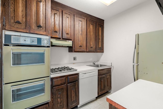85 E India Row Unit 31D, Boston, MA 02110 - kitchen featuring white appliances, under cabinet range hood, a sink, light countertops, and dark brown cabinetry