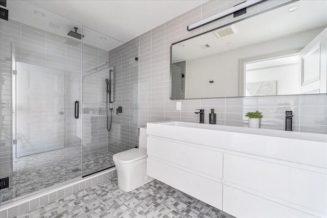 bathroom featuring tile walls, vanity, a shower with shower door, tile patterned floors, and toilet