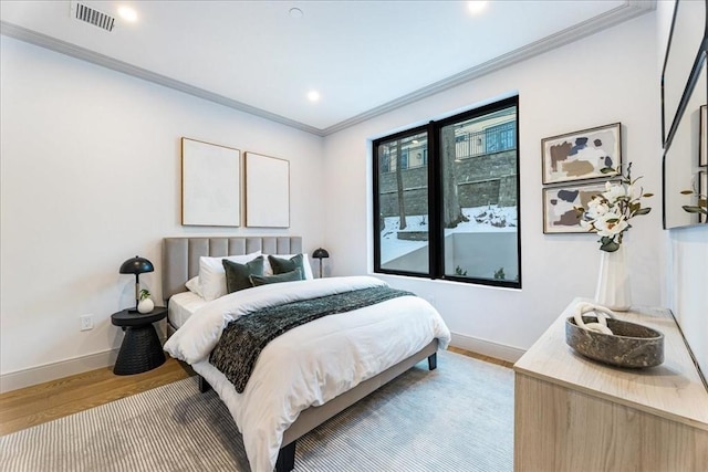 bedroom with crown molding and light hardwood / wood-style flooring