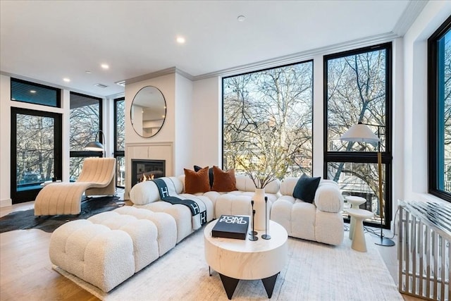 living room featuring radiator, a fireplace, crown molding, light hardwood / wood-style floors, and floor to ceiling windows