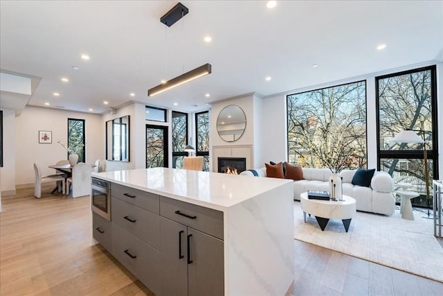 kitchen with light stone counters, hanging light fixtures, light hardwood / wood-style floors, and floor to ceiling windows