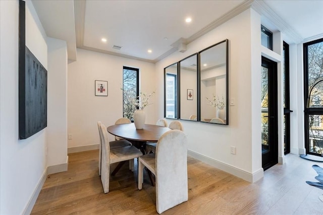 dining space with ornamental molding, a healthy amount of sunlight, and light hardwood / wood-style floors