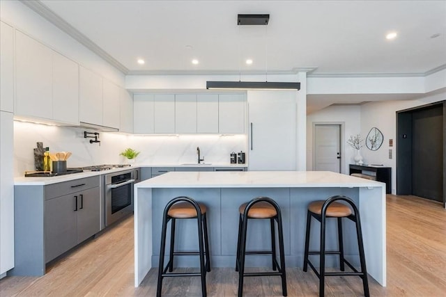 kitchen with white cabinetry, a kitchen breakfast bar, a center island, and appliances with stainless steel finishes