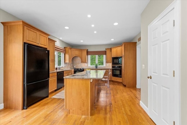 17 Fiddleneck Ln, Southborough, MA 01772 - kitchen with black appliances, a kitchen breakfast bar, a kitchen island with sink, light wood finished floors, and recessed lighting