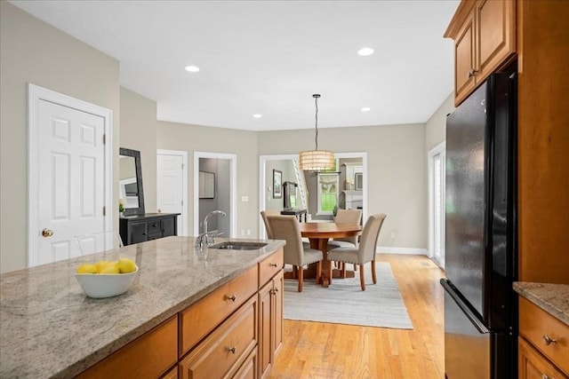 17 Fiddleneck Ln, Southborough, MA 01772 - kitchen featuring a sink, freestanding refrigerator, brown cabinets, light wood finished floors, and light stone countertops