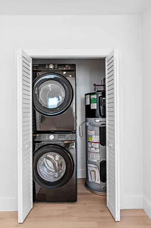 304 Paris St Unit 2, Boston, MA 02128 - laundry area featuring water heater, stacked washing machine and dryer, baseboards, and wood finished floors