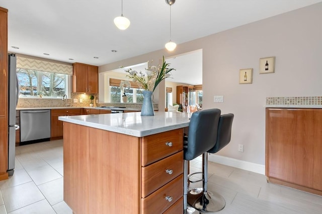 kitchen with a center island, decorative backsplash, appliances with stainless steel finishes, decorative light fixtures, and a kitchen bar