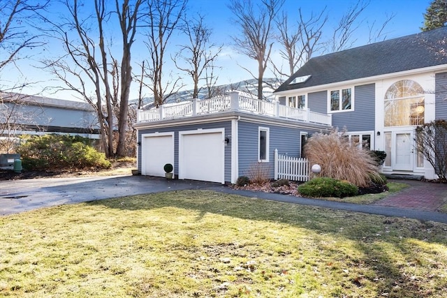 view of side of property with a lawn, a garage, and a balcony