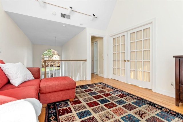 living room with french doors, vaulted ceiling, and hardwood / wood-style flooring