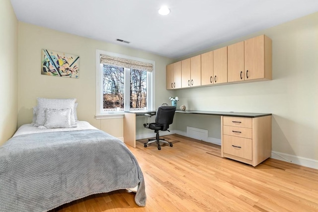 bedroom with light hardwood / wood-style flooring and built in desk