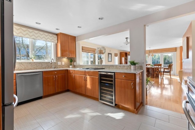 kitchen with decorative backsplash, light tile patterned floors, appliances with stainless steel finishes, kitchen peninsula, and beverage cooler