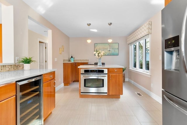 kitchen with beverage cooler, hanging light fixtures, and appliances with stainless steel finishes