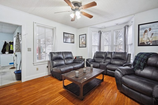 living room with a textured ceiling, wood-type flooring, and ceiling fan