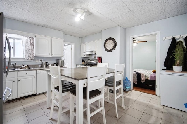 kitchen with white cabinetry, appliances with stainless steel finishes, light tile patterned floors, and a drop ceiling