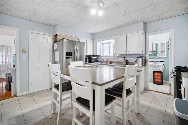 kitchen featuring sink, a breakfast bar area, light tile patterned floors, stainless steel appliances, and white cabinets