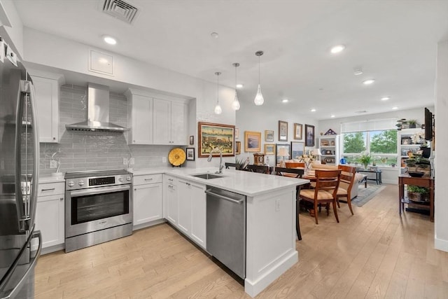 130 Broad Reach Unit 302, Weymouth, MA 02191 - kitchen featuring appliances with stainless steel finishes, wall chimney range hood, a peninsula, light wood-type flooring, and recessed lighting