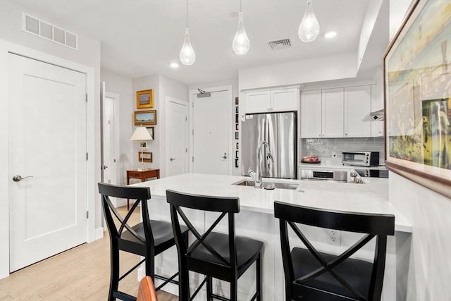 130 Broad Reach Unit 302, Weymouth, MA 02191 - kitchen with freestanding refrigerator, light countertops, white cabinetry, pendant lighting, and a peninsula