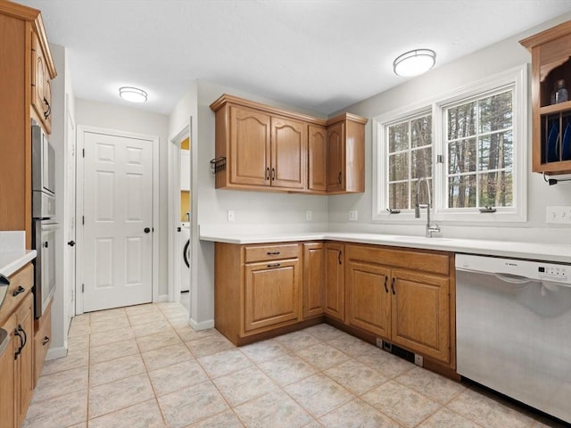 kitchen featuring brown cabinetry, stainless steel appliances, light countertops, and a sink