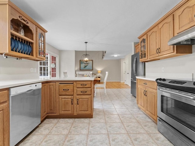 kitchen featuring a peninsula, stainless steel appliances, light countertops, glass insert cabinets, and under cabinet range hood