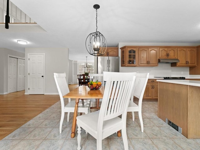 dining room featuring a notable chandelier, baseboards, visible vents, and light wood-type flooring