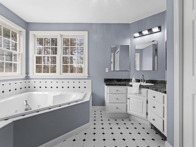 full bathroom featuring a jetted tub, vanity, and baseboards