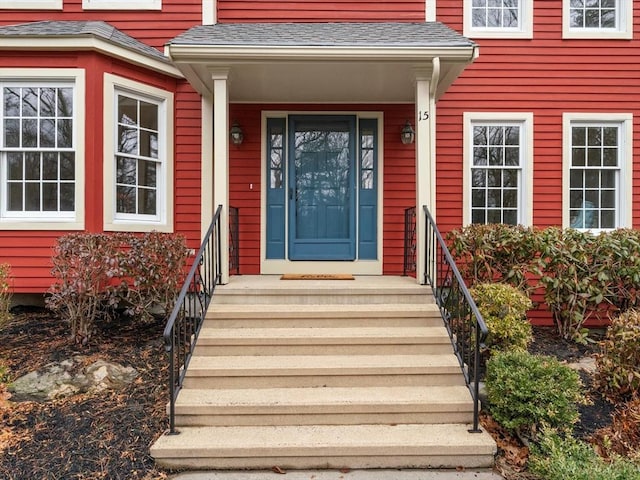 view of exterior entry with a shingled roof