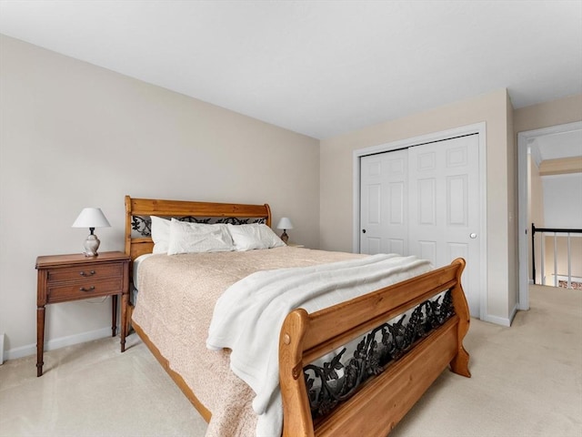 bedroom with a closet, light colored carpet, and baseboards