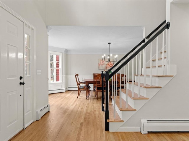 entrance foyer with a baseboard radiator, wood finished floors, and stairs