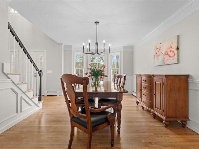 dining space with light wood-type flooring, an inviting chandelier, and ornamental molding