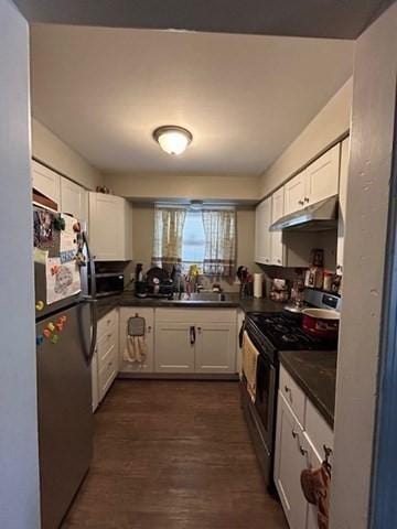 kitchen with appliances with stainless steel finishes, dark hardwood / wood-style floors, white cabinets, and sink