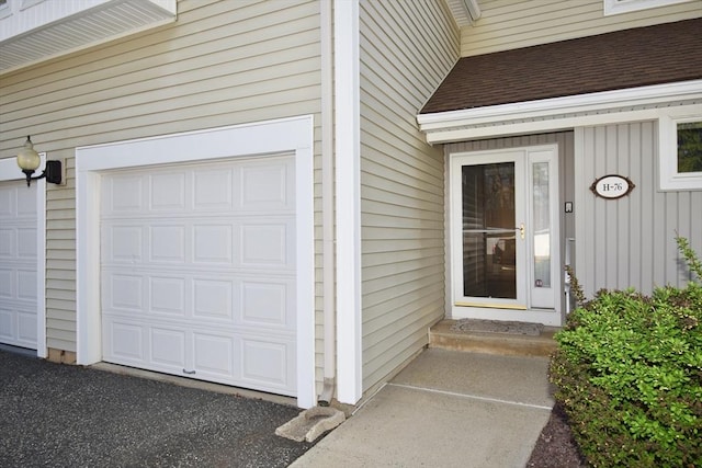property entrance with roof with shingles and a garage