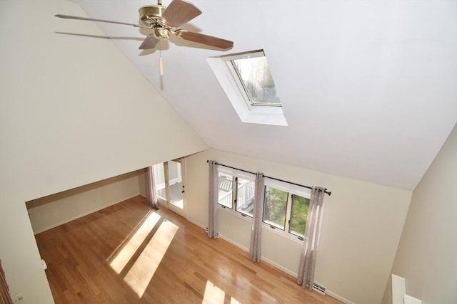 additional living space with light wood-style floors, a ceiling fan, baseboards, and lofted ceiling with skylight