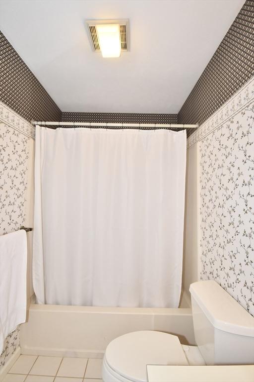 full bath featuring toilet, wallpapered walls, visible vents, and shower / bath combination with curtain