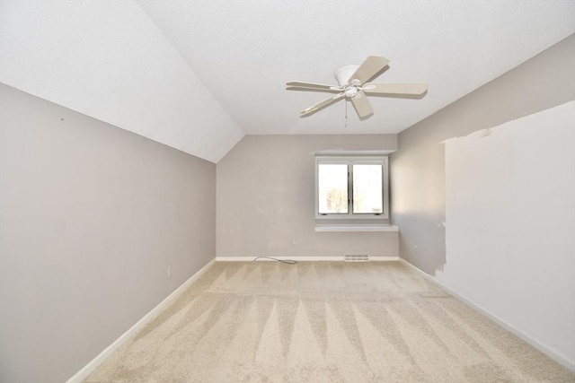 additional living space with visible vents, lofted ceiling, baseboards, light colored carpet, and a ceiling fan