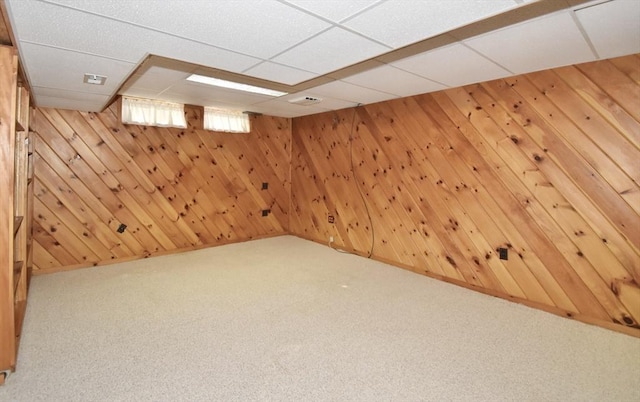 interior space featuring carpet floors, wood walls, and a drop ceiling