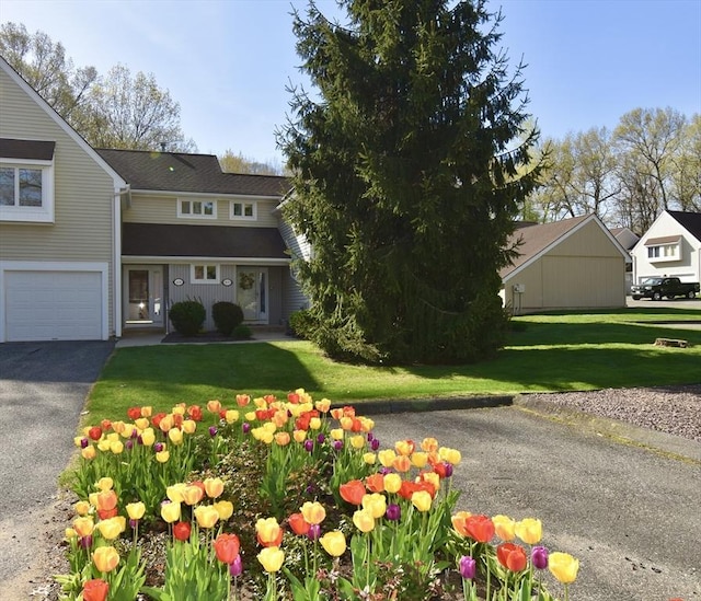 view of front facade with a garage, a front lawn, and aphalt driveway